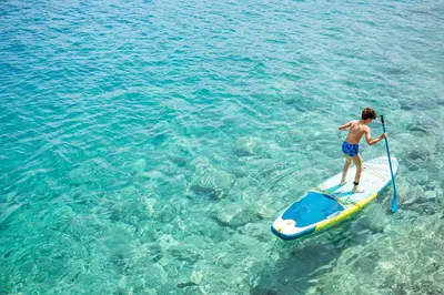 a man standing on a paddle board in the water at Villa Annouska in Halki