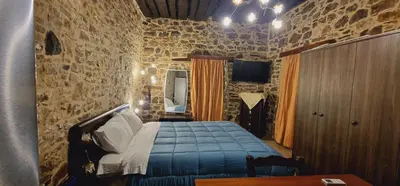 a bedroom with a bed and a stone wall at Marias House in Kritinía