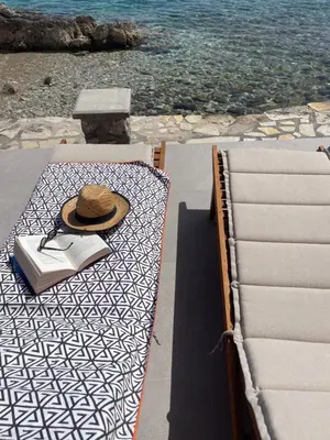 a hat and a book on a table next to the water at NUMĒNIA Seafront Property in Halki