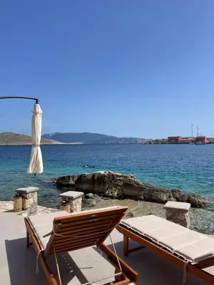 a beach chair and an umbrella and the ocean at NUMĒNIA Seafront Property in Halki