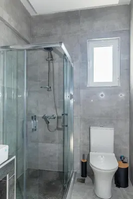 a bathroom with a shower and a toilet and a window at Katerina family Apartment in Archangelos