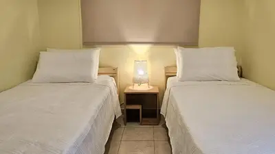 two beds in a room with a lamp on a table at The 20A Terminal Stay N Fly in Paradeísion