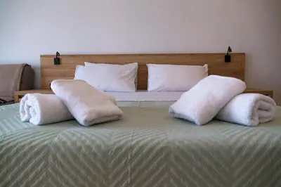 a bed with two white towels on top of it at Zen Beach Suite Faliraki in Faliraki