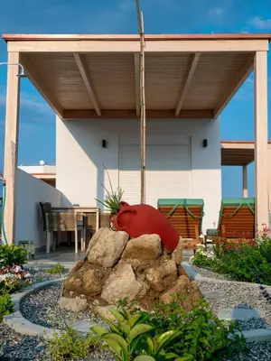 a red bird sitting on a rock in a garden at Zen Beach Suite Faliraki in Faliraki