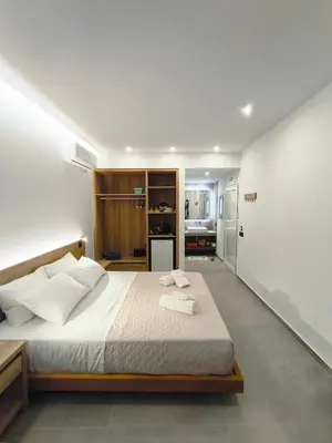 a bedroom with a large bed and a kitchen at Zen Beach Suite Faliraki in Faliraki