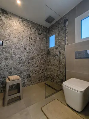a bathroom with a toilet and a glass shower at Zen Beach Suite Faliraki in Faliraki