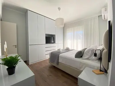 a white bedroom with a large bed and a window at SimplyCity Homestay Apartment 2 in Kremasti