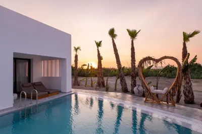 a swimming pool with chairs and palm trees at Martini Boutique Resort in Ialyssos
