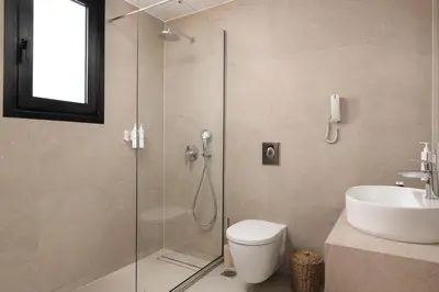 a bathroom with a shower and a toilet and a sink at Martini Boutique Resort in Ialyssos