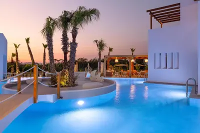 a pool with palm trees and a resort at Martini Boutique Resort in Ialyssos