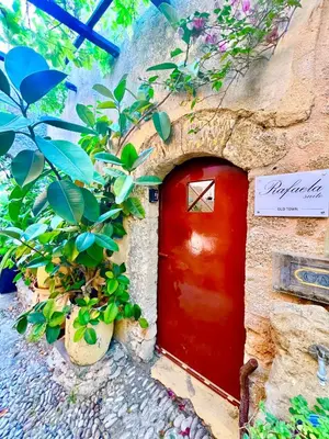 a red door in the side of a building with plants at Rafaela suite old town in Rhodes Town