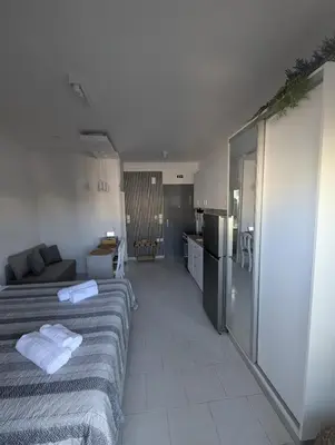 a living room with two beds and a kitchen at Pixel Palace in Rhodes Town