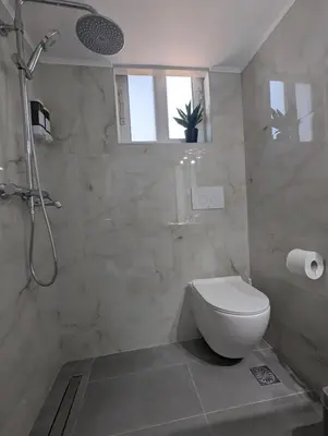 a bathroom with a toilet and a shower with a window at Pixel Palace in Rhodes Town