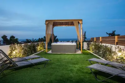 a gazebo with a table and benches on a lawn at Zafora Garden in Koskinou