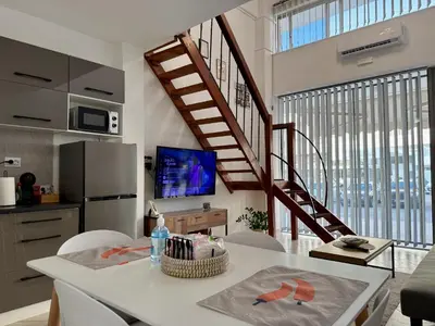 a living room with a table and a staircase at Polikseni Apartment Orfanidou in Rhodes Town