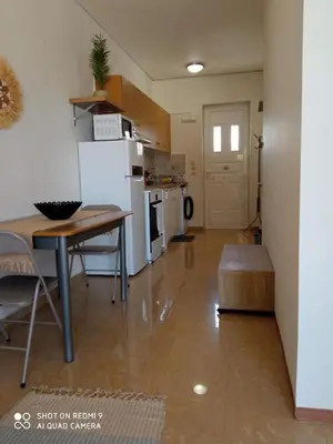 a kitchen and living room with a table and a refrigerator at Beach Sunset Apartment Ialisos in Ialyssos