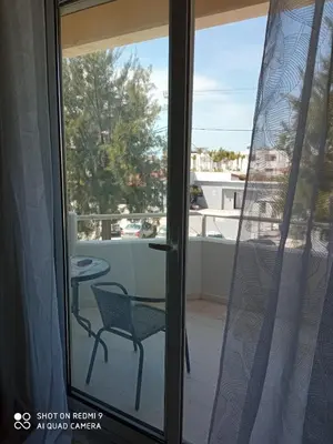 a sliding glass door with a chair on a balcony at Beach Sunset Apartment Ialisos in Ialyssos