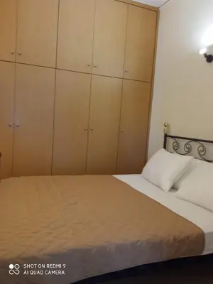 a bedroom with a bed with wooden cabinets at Beach Sunset Apartment Ialisos in Ialyssos