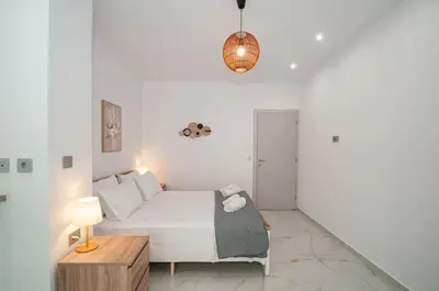 a white bedroom with a bed and a table at Asterashouse 2 in Rhodes Town