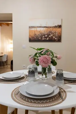 a white table with plates and flowers in a vase at Eviona Althea in Rhodes Town