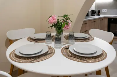 a white dining room table with white plates and pink flowers at Eviona Althea in Rhodes Town
