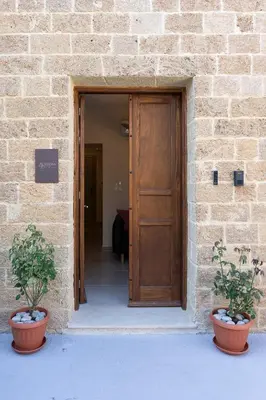 a wooden door in a brick building with two potted plants at Eviona Althea in Rhodes Town