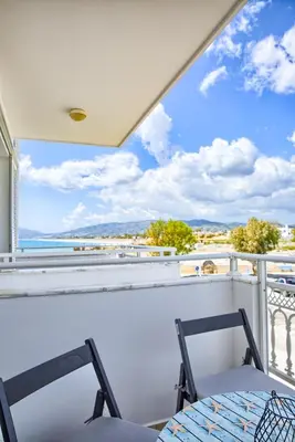 a balcony with a table and chairs and a view of the ocean at Aegean Breeze in Haraki