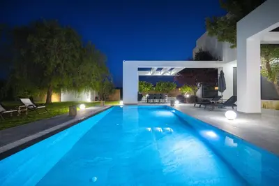 a swimming pool in the backyard of a house at night at Filerimos Panorama Villa in Pastida