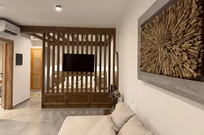 a living room with a couch and a television on a wall at Aurora Seaside Luxury Suite in Vrachonisída touArchangélou