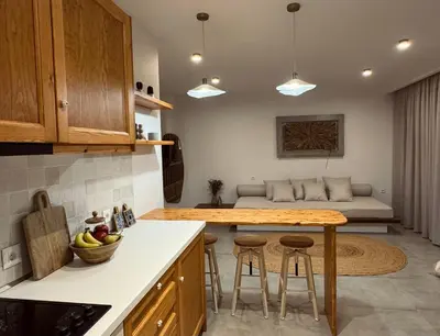 a kitchen with a table and a couch in the background at Aurora Seaside Luxury Suite in Vrachonisída touArchangélou