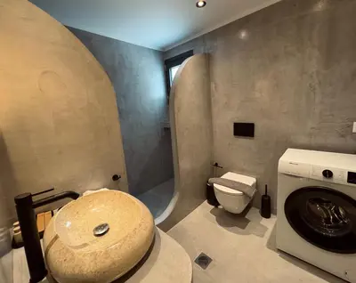 a bathroom with a washing machine and a toilet at Aurora Seaside Luxury Suite in Vrachonisída touArchangélou