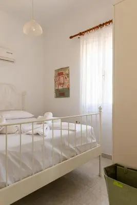a white bedroom with a bed and a window at Villa Dimosthenis in Symi