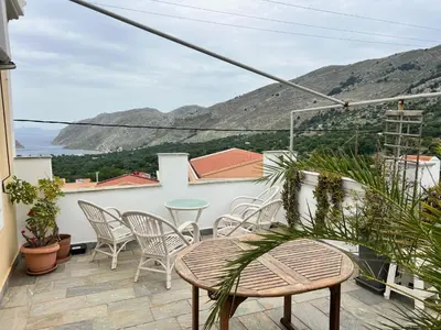 a balcony with chairs and a table and a view at Villa Dimosthenis in Symi