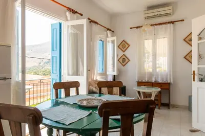 a dining room with a table and chairs and a window at Villa Dimosthenis in Symi