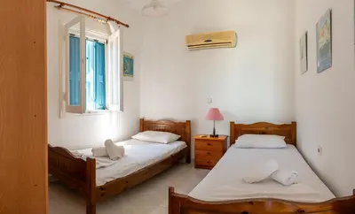 two twin beds in a room with a window at Villa Dimosthenis in Symi