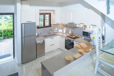 a kitchen with white appliances and a large window at Villa Arianna in Kalathos
