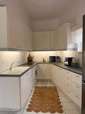 a kitchen with white cabinets and a rug on the floor at Andri's Garden House in Psinthos