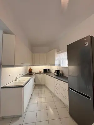 a kitchen with white cabinets and a stainless steel refrigerator at Andri's Garden House in Psinthos