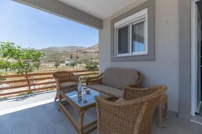 a balcony with wicker chairs and a table with a view at Pelagos in Vrachonisída touArchangélou