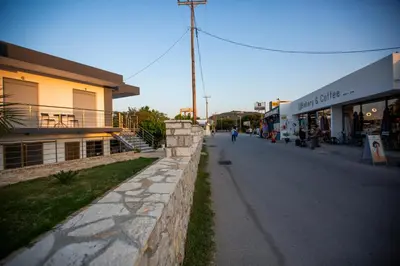 a street with a stone wall next to a building at RENI APARTMENT Faliraki in Faliraki