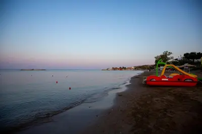a boat on a beach next to the water at RENI APARTMENT Faliraki in Faliraki