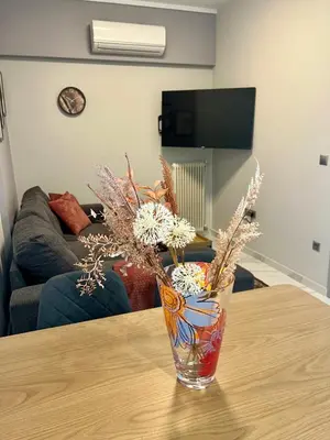 a glass vase with flowers sitting on a table at Paradise City Apartment 2 in Rhodes Town
