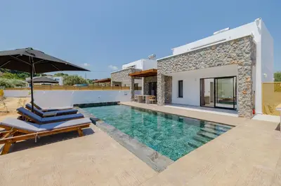 a villa with a swimming pool with chairs and an umbrella at Brillante VIllas by Renthub in Kolimbia
