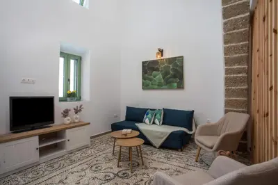a living room with a blue couch and a tv at Nouvelle15 Cozy House with Private Pool in Koskinou