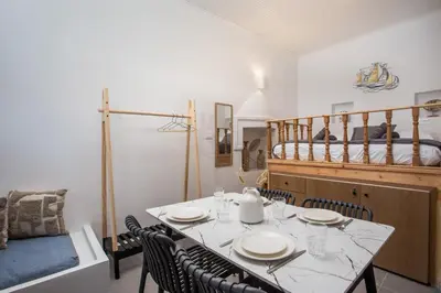 a dining room with a table and chairs and a bed at Port Elegance Residence - Halki in Halki