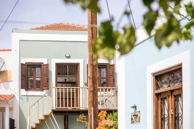 a white house with windows and a balcony at Port Elegance Residence - Halki in Halki