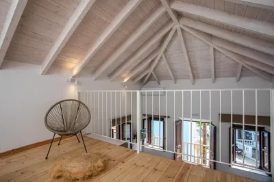a room with a wooden ceiling and a chair at Port Elegance Residence - Halki in Halki
