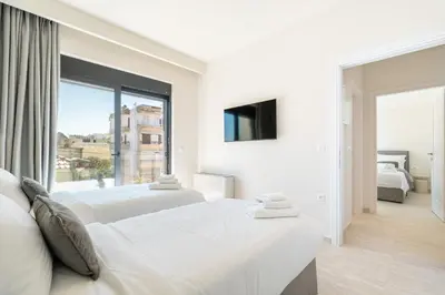 a white bedroom with two beds and a window at D&R Boutique Apartments Central in Rhodes Town