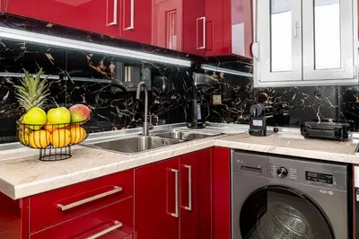 a kitchen with red cabinets and a sink with a basket of fruit at Avli Village House with Private Jacuzzi in Paradeísion