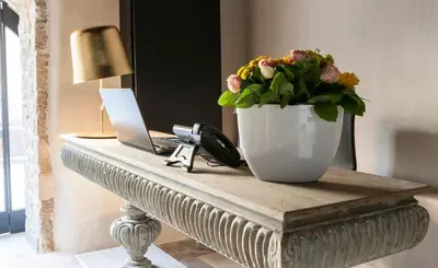 a table with a vase of flowers and a laptop at Allegory Boutique Hotel in Rhodes Town
